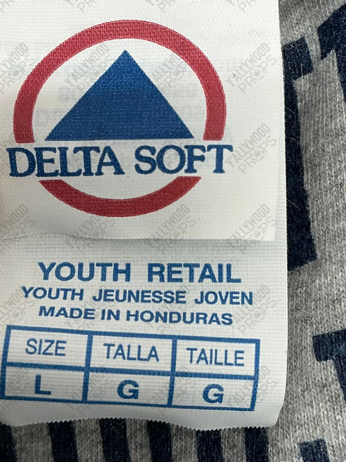 White care label with Delta Soft logo, blue triangle, red circle, and size L youth retail information printed on fabric.