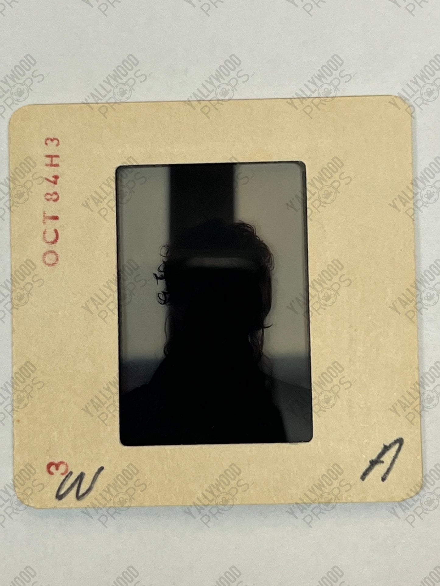 35mm film slide with silhouetted profile of a person with dark hair against a light background, mounted in tan cardboard fram