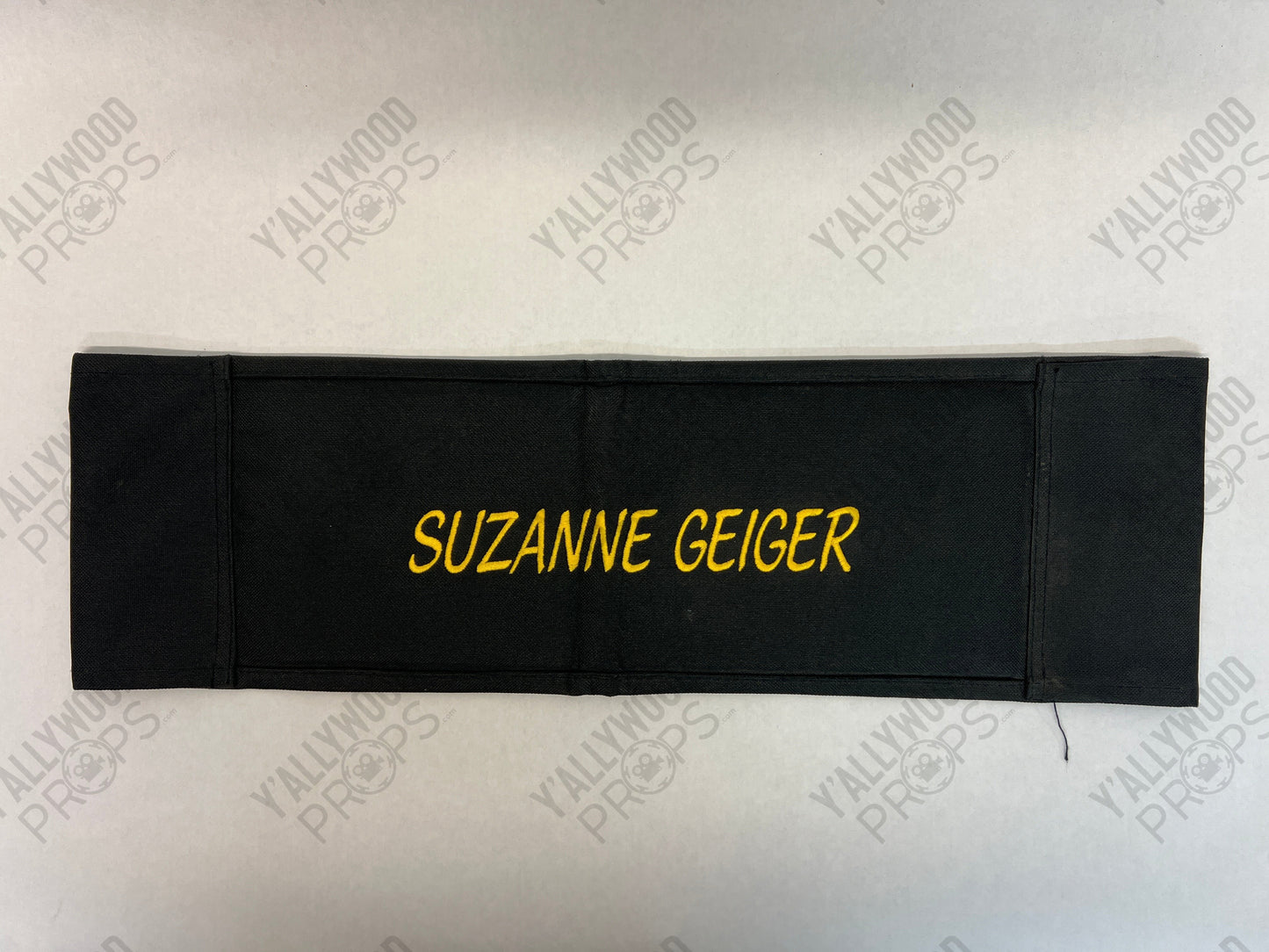 Black chair back with "SUZANNE GEIGER" text in yellow lettering.